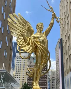 Golden Boy statue of a winged male figure holding lightning bolts and a coiled cable in Dallas.