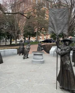 Virginia Women\'s Monument with life-sized metallic statues arranged in a circle, including a central figure holding a Votes for Women banner.