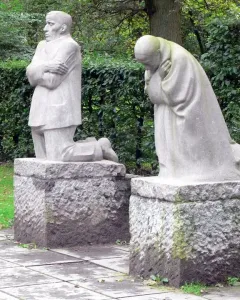 The Mourning Parents sculpture with two kneeling stone figures on separate pedestals outdoors.