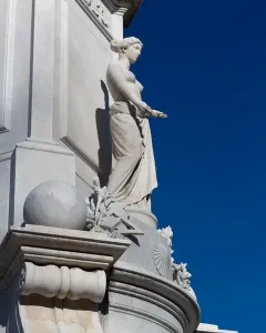 Peace Monument with a draped marble female figure and carved base against a blue sky.