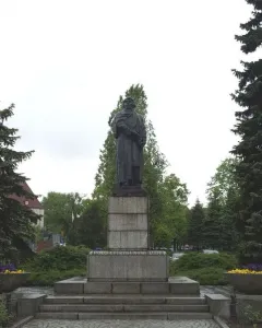 Mickiewicz Monument, a dark statue of a bearded man holding a book on a tall stone pedestal in a park.