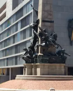 Monumento a Júlio de Castilhos with a tall stone obelisk on a multi-tiered base and bronze figures around it.