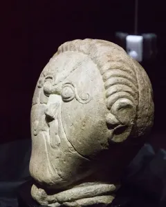 Mšecké Žehrovice Head, a carved stone head with stylized eyes, a prominent nose, and patterned hair and cheek details.