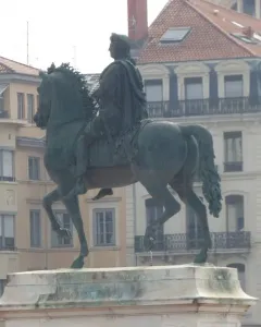 Louis XIV equestrian statue on a stone pedestal in Place Bellecour, with city buildings in the background.
