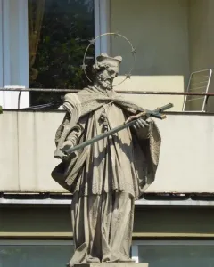 Stone statue of Saint John of Nepomuk holding a crucifix and palm frond, with a halo of stars.