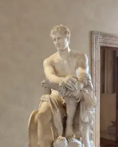 Ludovisi Ares seated in white marble, with a small winged child at his leg and a shield beside him.