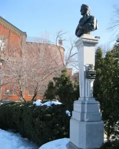 La mort de Dante monument with a dark bust on a tall stone pillar in a snowy park
