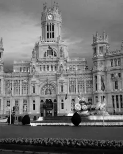 The Cibeles Fountain with a classical figure in a chariot drawn by lions in front of a grand building.
