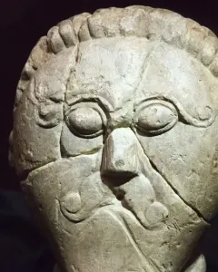 Mšecké Žehrovice Head, a carved stone head with stylized eyes, a prominent nose, and patterned hair and cheek details.