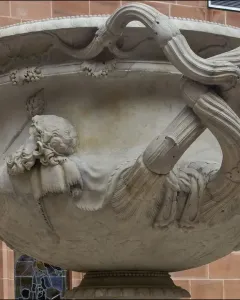 Side view of the Warwick Vase, showing its ornate carved heads and intertwined vine-like handles.