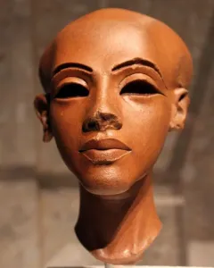 Head of a Princess, a reddish-brown stone sculpture with a slender neck, dark almond-shaped eyes, arched brows, and damaged nose bridge.