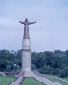 Mother Patroness monument in Cheboksary, a robed bronze figure with outstretched arms atop a tall pillar above landscaped steps and lawns.