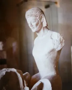 Fragmentary marble head and upper body of the Rampin Rider with an archaic smile, beard, and detailed hair.