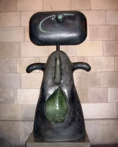 Femme by Joan Miró, a dark abstract sculpture with a rounded head, curved arm-like forms, and a green teardrop shape on the front.