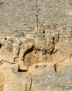 Madara Rider rock relief showing a horseman on horseback, a dog running ahead, and a faint fallen figure below.
