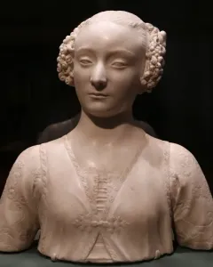 Marble bust of a young woman with tightly curled hair and an ornate carved garment.
