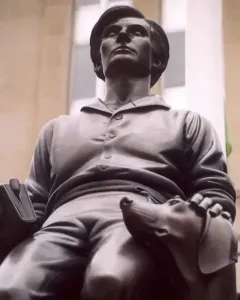 Abraham Lincoln: The Hoosier Youth bronze sculpture of a seated young man holding a book, with a dog resting beside him.