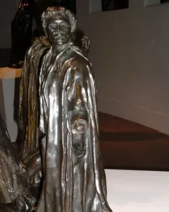 Bronze sculpture of Jean de Fiennes by Auguste Rodin, shown in a draped cloak with one hand holding a ring-like object.