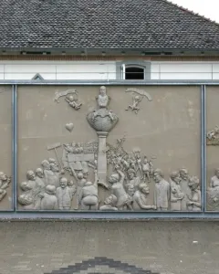 Ludwigs Erbe stone relief with three panels showing a crowded central monument scene and smaller figures on either side.