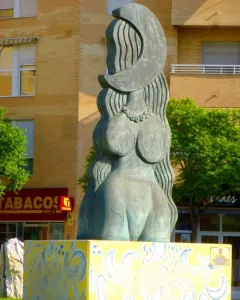 Dona Lluna bronze sculpture of a stylized female figure with a crescent moon above her head on a yellow patterned pedestal.