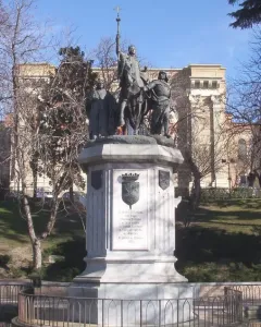 Monument to Isabella of Castile showing a bronze equestrian statue on an ornate marble pedestal in a shallow pool.