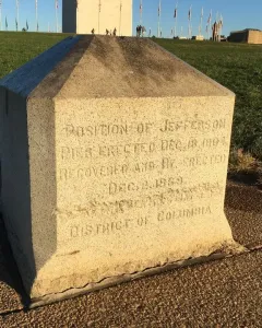 Jefferson Pier stone monument with carved lettering on a paved area near grass.