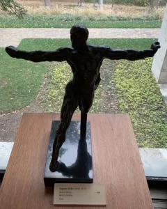 Standing Mercury, a dark bronze nude male sculpture posed with one leg lifted and both arms extended.