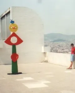 The Caress of a Bird sculpture with stacked colorful abstract shapes on a green pillar.