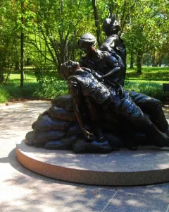 Vietnam Women\'s Memorial bronze sculpture showing two female figures tending a prone figure on a circular stone base.