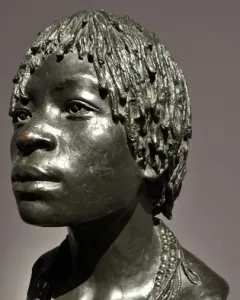 Woman of Central Africa bronze bust with short textured hair and layered beaded necklaces, shown in three-quarter profile.