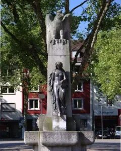 Mutter Kinzig monument with a stone eagle atop a tall shaft and a dark female figure below.