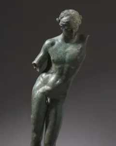 The Cleveland Apollo bronze statue with a green patina, standing on a simple base against a dark background.