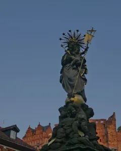 Kornmarkt Madonna sculpture of a crowned woman holding a child, standing on a globe above an ornate base with cherubs.