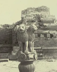 Lion Capital of Ashoka sculpture with two lions and a partially visible third lion head atop a decorated capital with wheels.