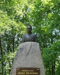 Bronze bust of Józef Piłsudski in military uniform on a rough stone pedestal with an inscription plaque.