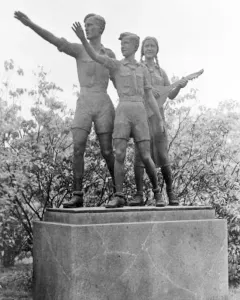 Youth Monument showing three young figures on a stone pedestal, with one male figure saluting and a female figure holding a lute-like instrument.