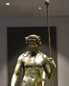 Tiber Dionysus bronze statue of a nude male figure holding a staff and wearing a wreath.