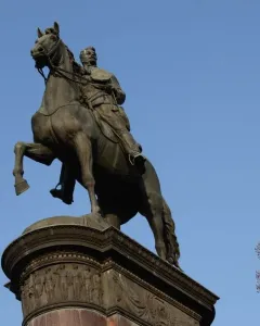 Monument to Mykola Shchors, a bronze equestrian statue on an ornate pedestal against a blue sky.