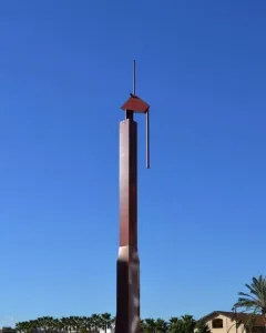 The Pink Panther sculpture rises from a shallow reflecting pool beneath a clear blue sky.