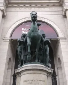 Theodore Roosevelt Equestrian Statue with a rearing horse and two standing figures in front of the American Museum of Natural History.