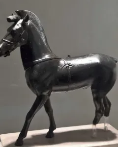 Bronze horse statuette from Olympia shown in profile on a pedestal.