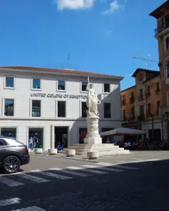 Monumento dell\'Indipendenza statue of a draped female figure holding a spear in front of a historic brick building.