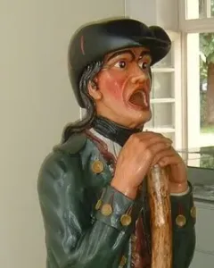 Aschaffenburger Maulaff, a painted wooden figure in a green coat and dark cap, leaning on a staff with its mouth open.