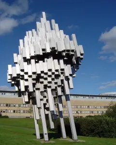 Norra skenet stainless steel sculpture with reflective metal bars rising diagonally on a lawn.