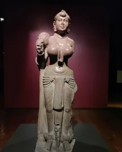 Didarganj Yakshi standing stone statue holding a fly-whisk, with necklaces, a headdress, and a draped lower garment.
