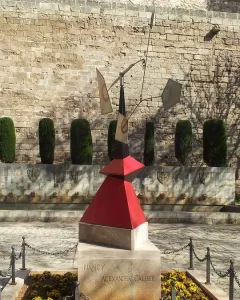 Nancy, a large abstract metal sculpture with red, black, and silver geometric forms on a stone pedestal in an outdoor courtyard.