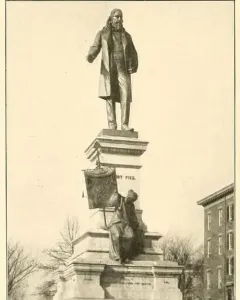Albert Pike Memorial with a large statue of a bearded man atop a multi-tiered stone pedestal, with a smaller seated bronze figure below.