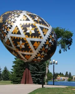 Vegreville pysanka egg sculpture with geometric black, gold, and white patterns outdoors.