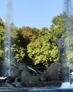 The Fountain of Neptune in Madrid with Neptune standing on a shell, flanked by two sea-horse figures and surrounded by jets of water.