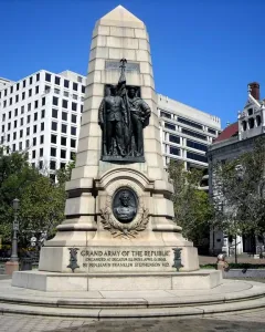 Stephenson Memorial with bronze figures of two men in military uniforms holding a flag above a circular medallion on a tiered stone base.